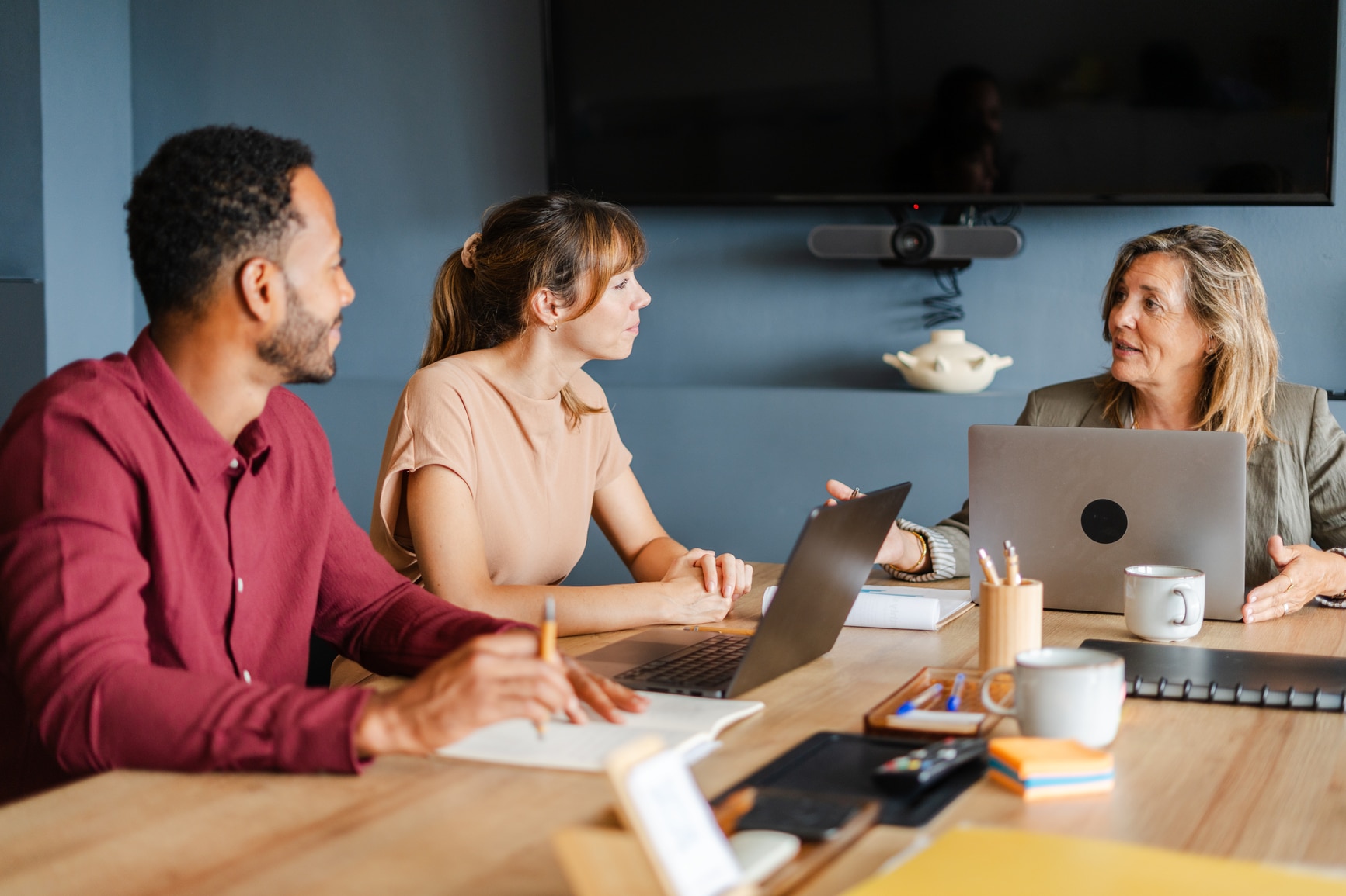 A group of diverse colleagues discussing a business plan in an office environment, highlighting how skills based hiring can bring together diverse teams of talent individuals to drive organisational success