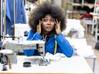 An image of an employee working with a sewing machine, looking stressed.